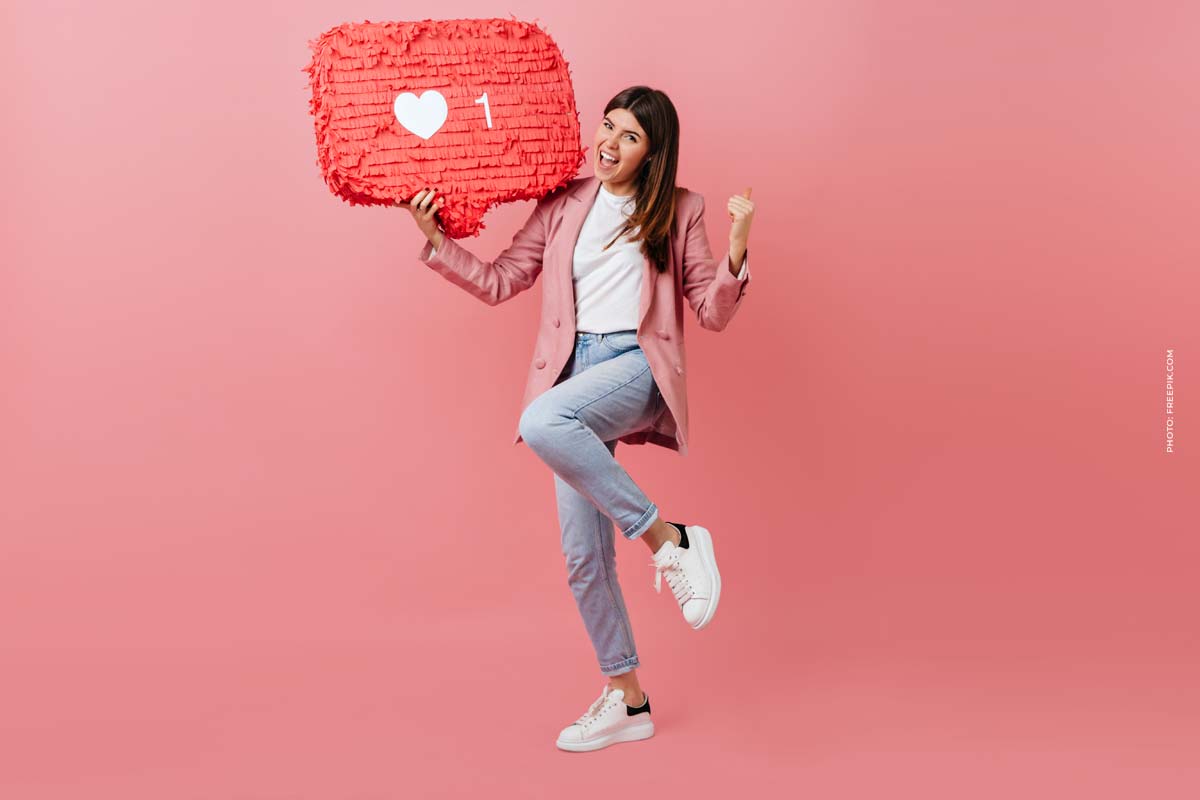girl enjoying social network feedback studio shot young woman dancing with like icon pink background